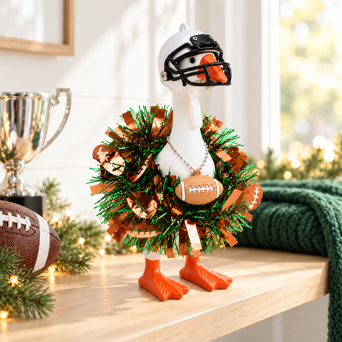 Little Honk Desk Goose wearing a football fan outfit beside a trophy and football