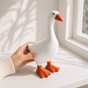Little Honk desk goose held by hand near a sunlit window